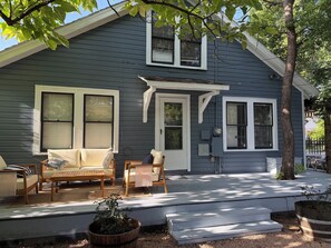 A house with a porch, outdoor seating, and a potted plant. - 3 bedroom charming Heights cottage for relaxing under the trees (Houston)