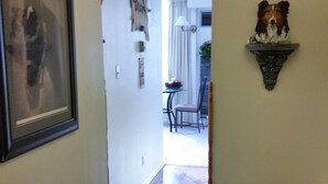 A hallway with a patterned rug, a framed picture on the wall, and a decorative wall piece.