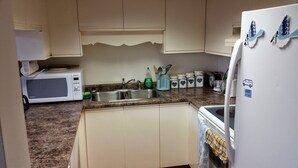A kitchen with white cabinets, a microwave, a sink, and a refrigerator.