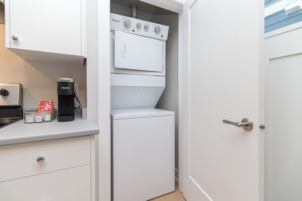 A compact kitchen with a coffee maker, a microwave, and a built-in washer and dryer.