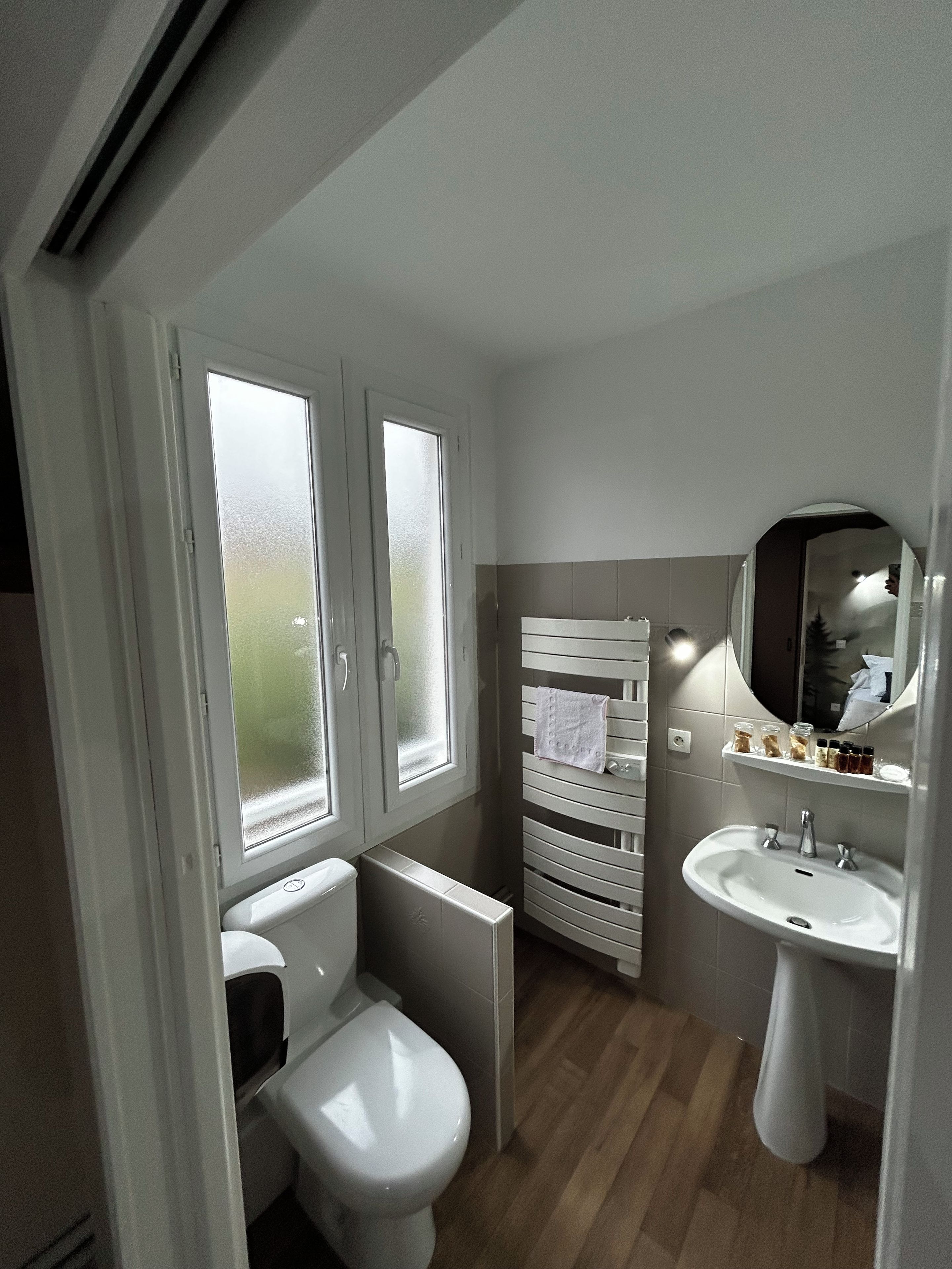 A compact bathroom with a toilet, a sink, and a window.