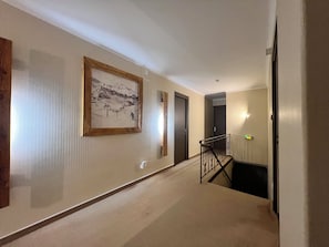 A hallway with a framed picture, a staircase, and a door.