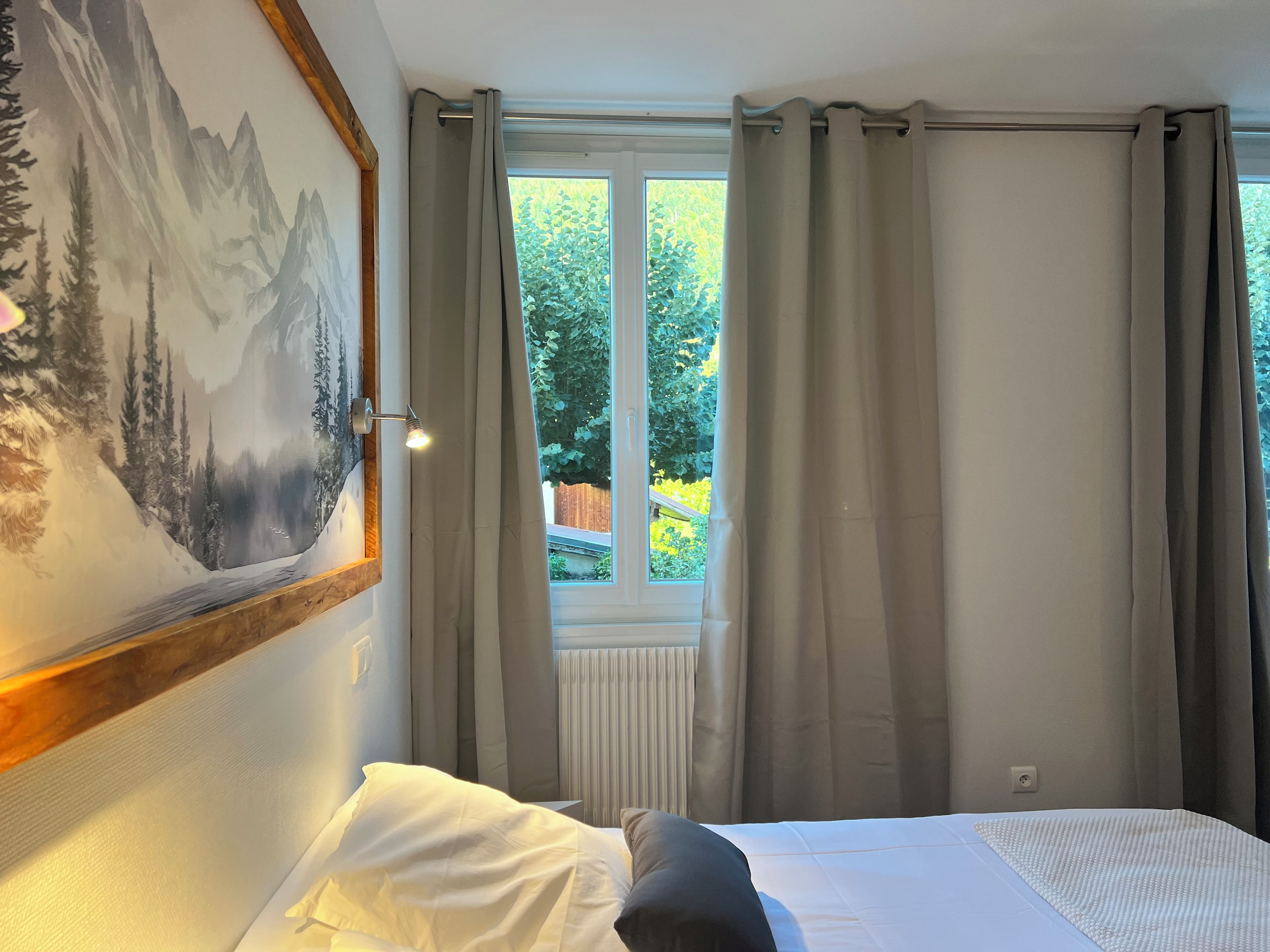 Une chambre à coucher avec un lit, une fenêtre avec des rideaux et un tableau accroché au mur.
