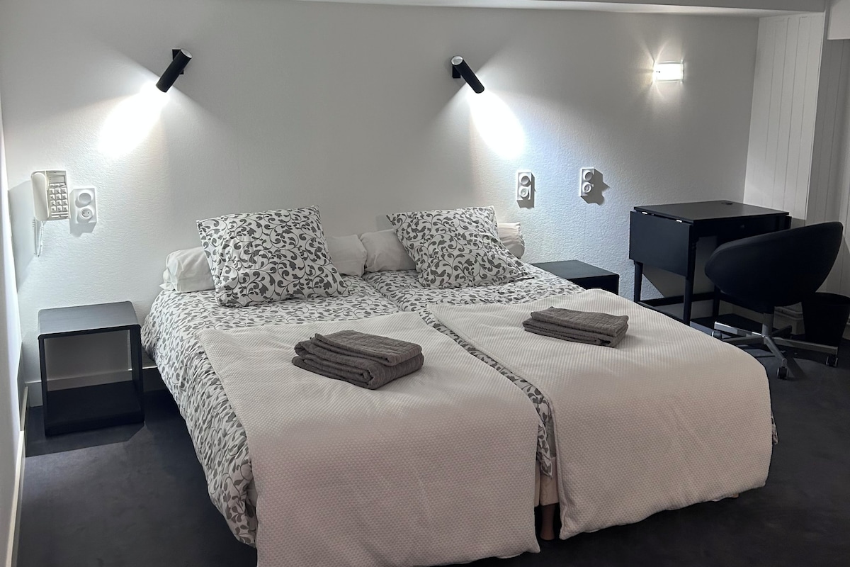 A bedroom with a bed, bedside tables, a desk, and a chair.