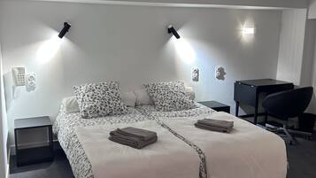 Een slaapkamer met een bed, nachtkastjes, een bureau en een stoel.