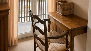 A room with a wooden table, a wicker basket, a chair, and a view of a balcony with a railing. - VICC (Faverges-Seythenex)