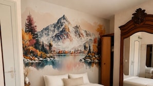 A bedroom with a bed, a large mirror, and a wall mural of a mountain landscape. - VICC (Faverges-Seythenex)