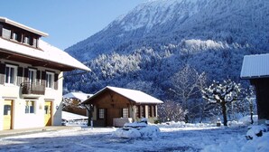 A snow-covered mountain with a building in the foreground. - VICC (Faverges-Seythenex)