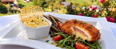 Un repas composé d’une escalope panée, de haricots verts et d’une portion de purée de pommes de terre, le tout servi dans une assiette blanche.