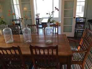 A wooden dining table with chairs, surrounded by glass vases with flowers.