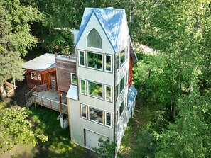 A multi-story building with a steep roof, surrounded by dense greenery. - Alice’s Treetop Retreat Of Chena Hot Springs (Fairbanks)