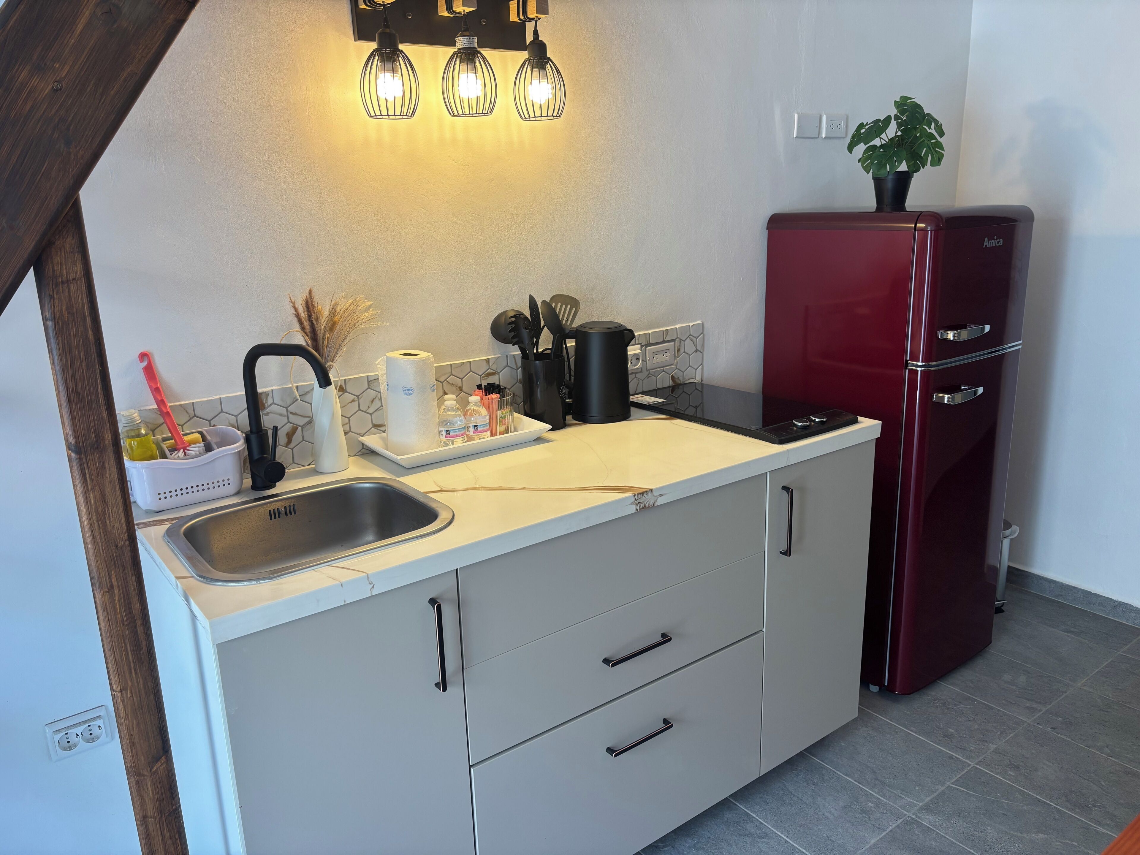 Eine kleine Küche mit Spüle, Arbeitsplatte und einem roten Kühlschrank.