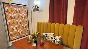 A room with a sofa, a table with a vase and card, a patterned wall, and a lamp. - Authentic Rincon, a touch of vintage charm (Rincon)