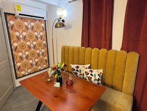 Ein Zimmer mit einer Couch, einem Tisch mit Vase und Karten, einer Wand mit Muster und einer Lampe.