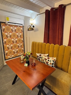 A room with a wooden table, a sofa, a patterned wall, and a radiator.
