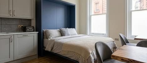 A compact bedroom with a bed, bedside table, and a window.
