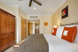 A hotel room with a bed, a wardrobe, a ceiling fan, and a painting on the wall. - Villa Del Arco 1 bedroom Suite in Cabo San Lucas during Bisbee Week (Cabo San Lucas)