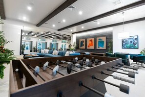 Un espacio interior moderno con una mesa de fútbol, zona de estar y obras de arte en las paredes.