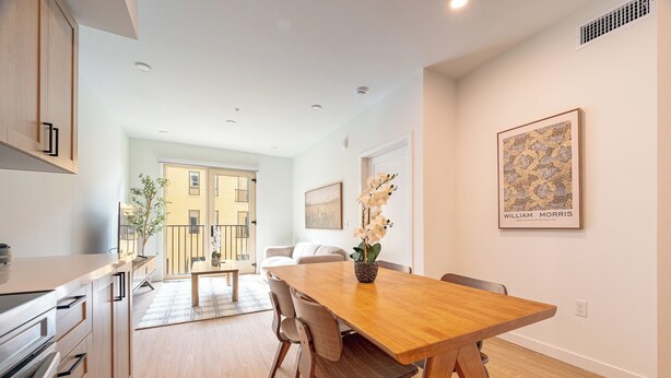 A modern kitchen with wooden cabinets and a dining area with a wooden table and chairs.