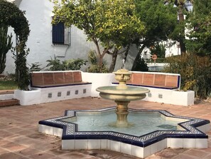A courtyard with a fountain, seating area, and a white building with a blue window. - Charming Andalusian-style house in the heart of Marbella (Marbella)