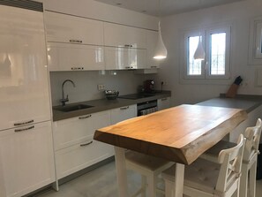 Eine moderne Küche mit weißen Schränken, einem Holztresen und einem Fenster mit Tageslicht.