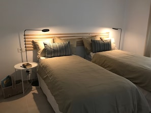 Ein Doppelbett mit Kopfteil, Nachttischen und einer Lampe.