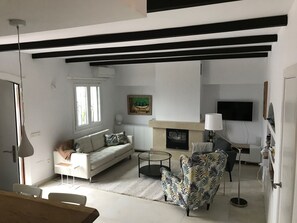 Una sala de estar moderna con un sofá, un sillón, una chimenea y un televisor de pantalla plana.
