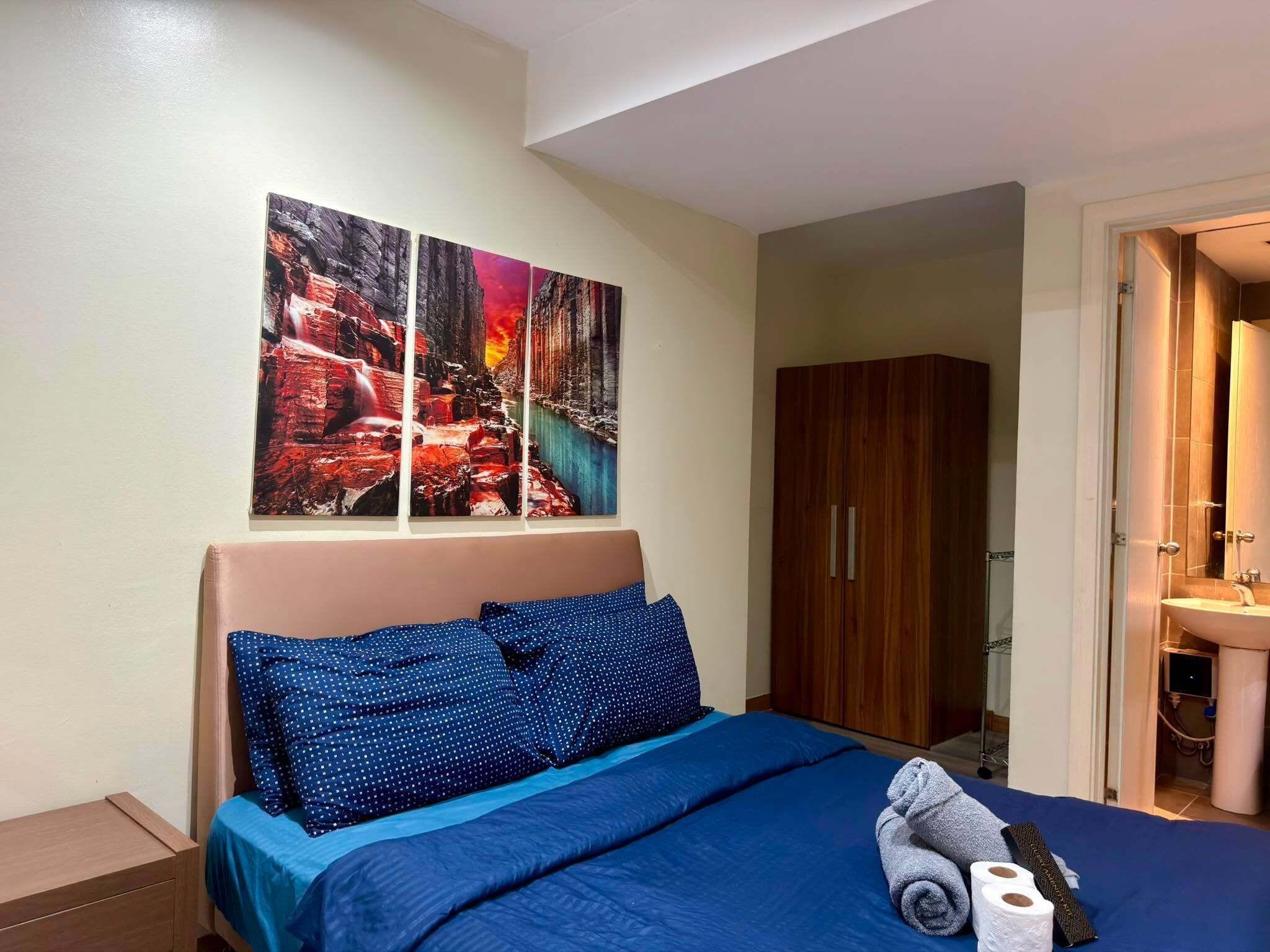 Une chambre à coucher avec un lit, une armoire et une salle de bain visible à travers une porte ouverte.