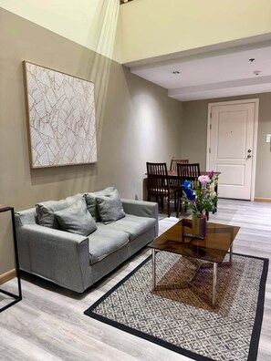 Una sala de estar con un sofá gris, una mesa de centro y un comedor con sillas de madera.