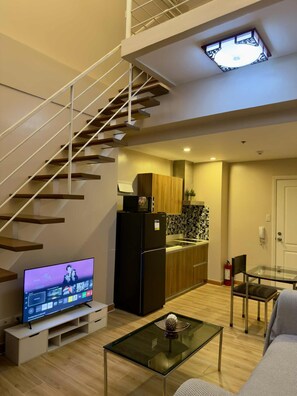Un apartamento moderno con una escalera, una cocina, un comedor y una sala de estar con televisor de pantalla plana.