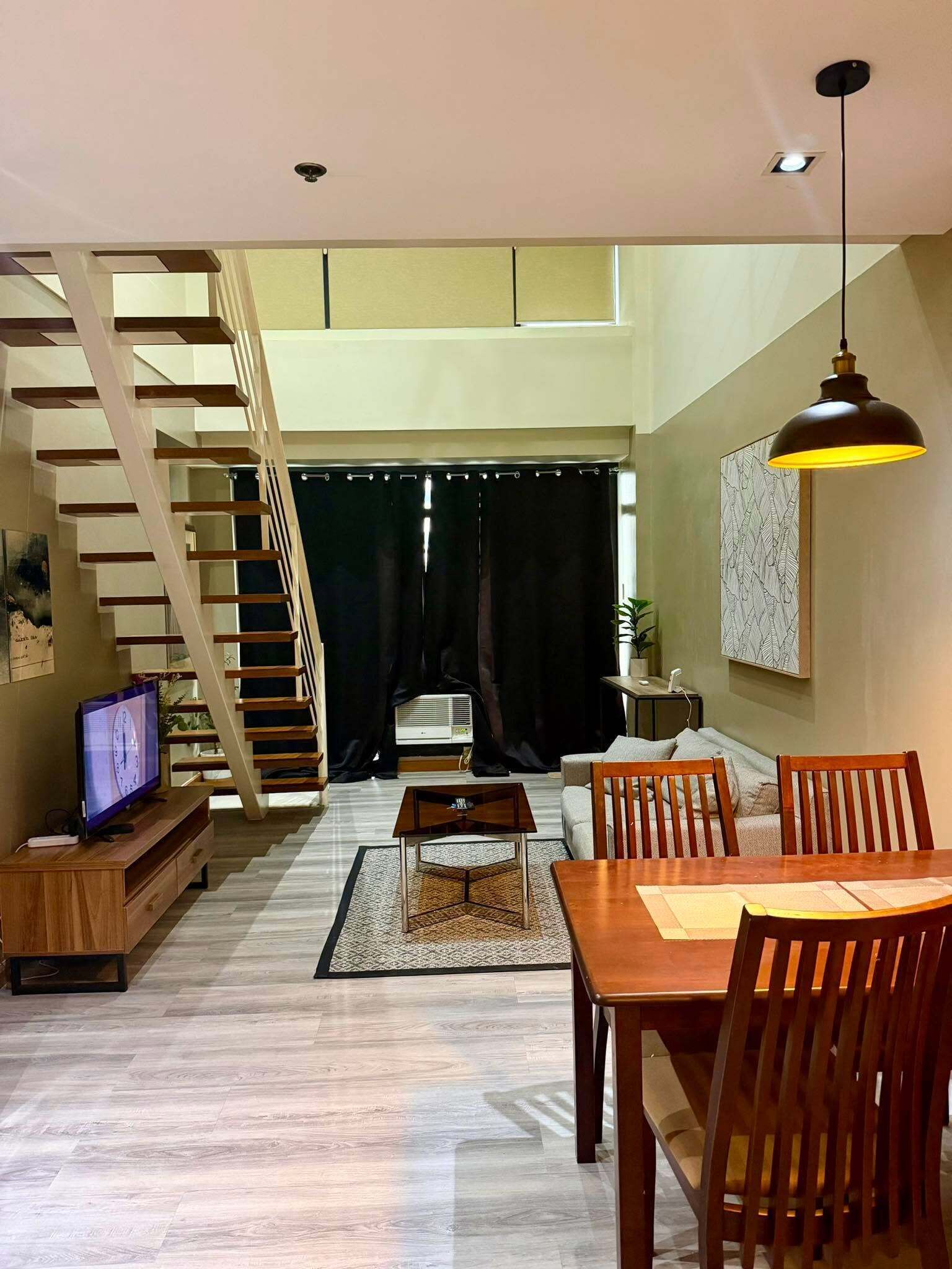 A spacious living area with a staircase, a dining table, and a television.