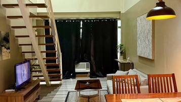 A spacious living area with a staircase, a dining table, and a television.