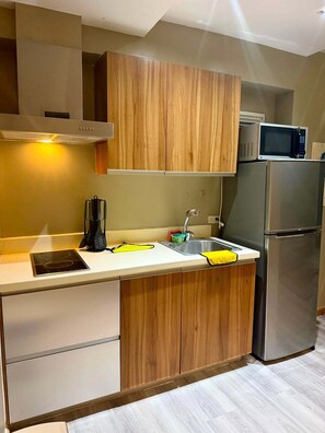 Una cocina moderna con armarios de madera, un refrigerador de acero inoxidable, un microondas y un lavamanos con una toalla amarilla.