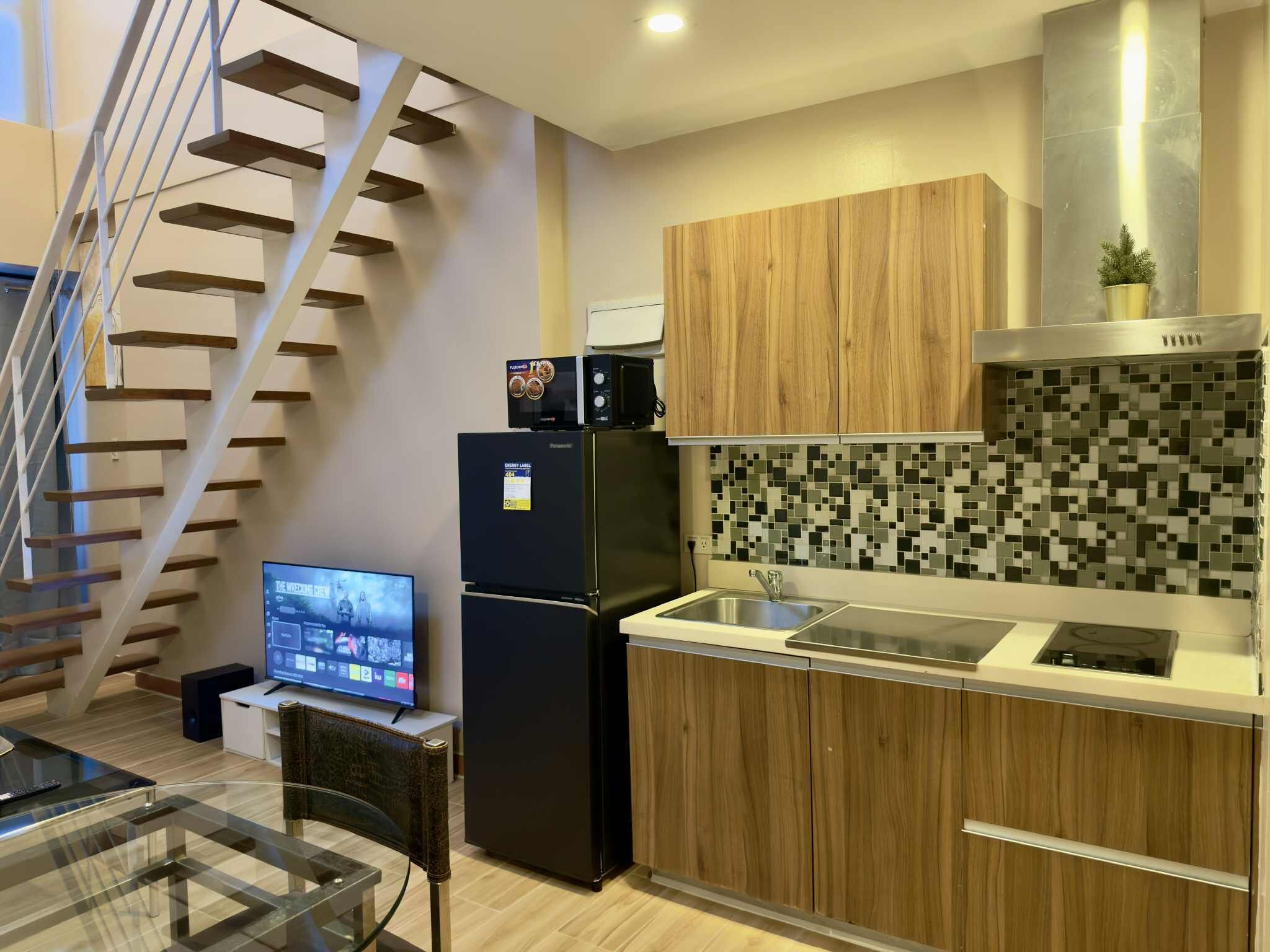 Una cocina moderna con microondas integrado, refrigerador y salpicadero de azulejos.