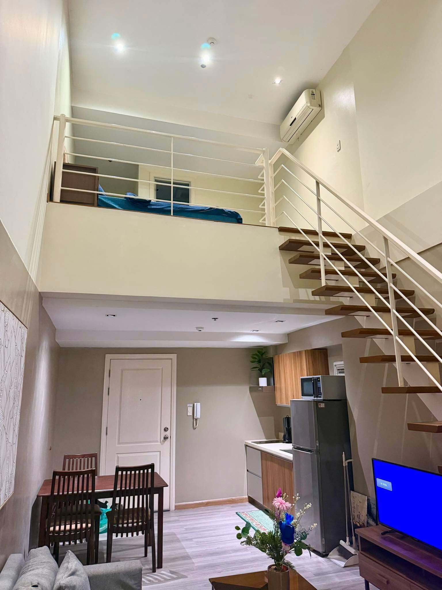 A two-story apartment with a staircase, a dining area, a kitchen, and a living room.