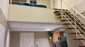 A two-story apartment with a staircase, a dining area, a kitchen, and a living room.