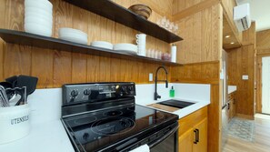 A kitchen with wooden cabinetry, a black stove, and a white countertop.
