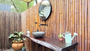 A bathroom with a stone sink, a mirror, a faucet, and a wooden wall.