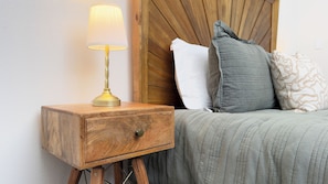 A wooden bedside table with a lamp, a drawer, and a bed with pillows and a quilted blanket. - Gorgeous Newly Renovated Getaway 2BR/ 2BA near Blue Spring State Park (Orange City)