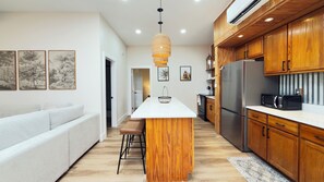 A modern kitchen with wooden cabinets, a stainless steel refrigerator, and a white countertop.