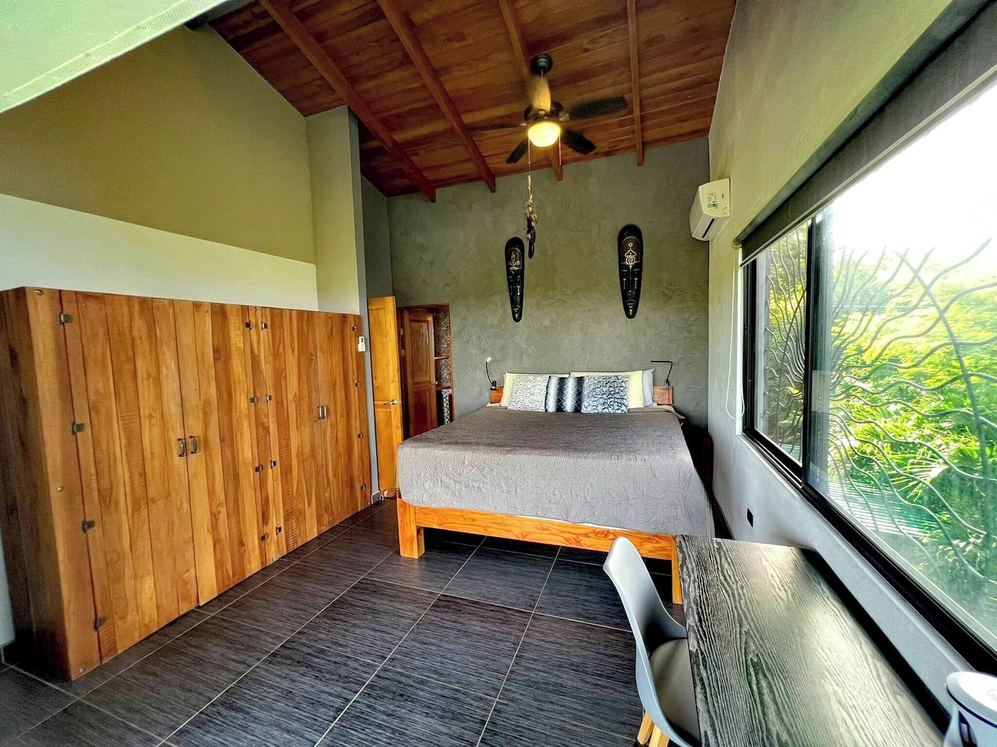 Un dormitorio con cama, armario de madera y ventana con vistas.