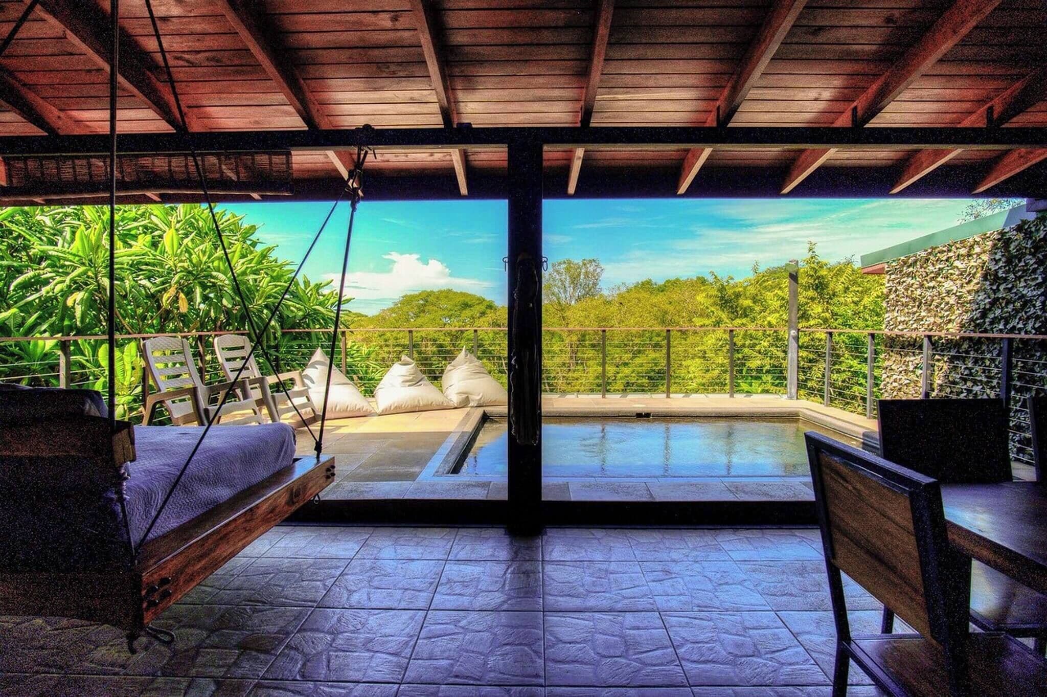 Une chambre avec un lit, une petite table et une vue sur une piscine extérieure.