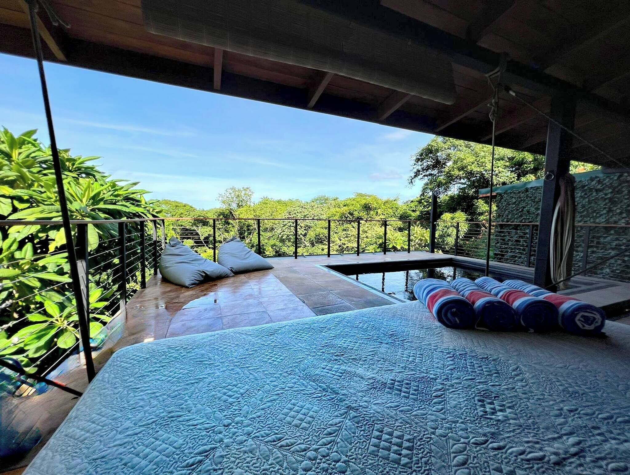 A bedroom with a large bed, a view of the outdoors, and a balcony with a railing.