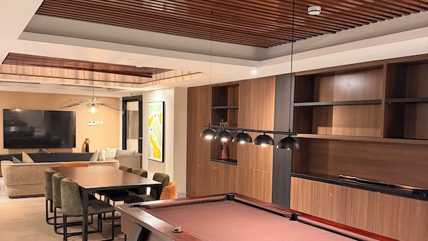 A billiards table in a modern room with a wooden ceiling, a dining area with chairs, and a television. - BridgeView Cantonments (Accra)