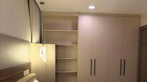 A bedroom with a large bed, built-in shelving, and a wardrobe. - BridgeView Cantonments (Accra)