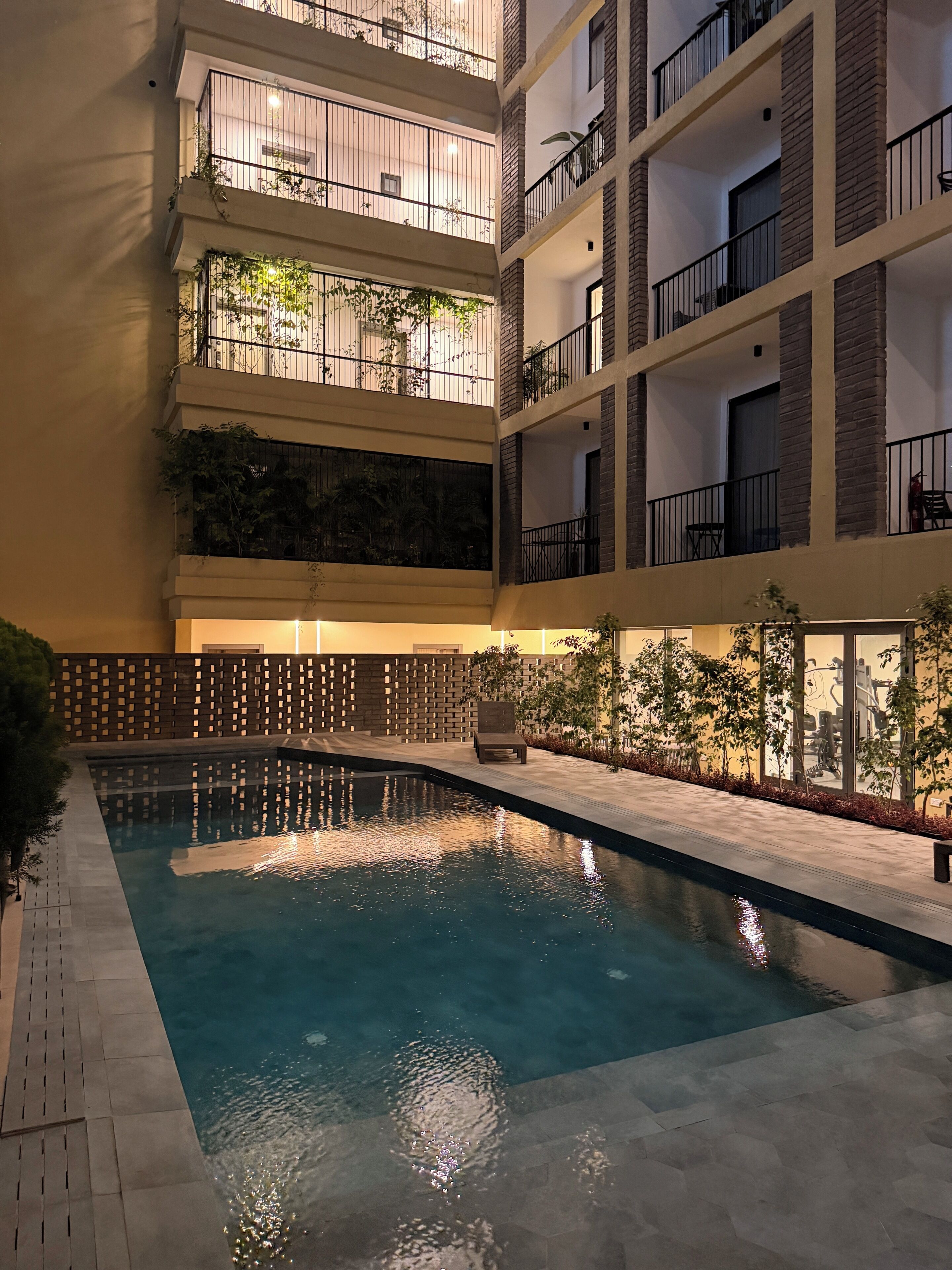 Una piscina interior de varios niveles con agua cristalina, rodeada por un muro de ladrillo y una valla de madera.