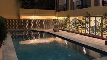 Una piscina interior de varios niveles con agua cristalina, rodeada por un muro de ladrillo y una valla de madera.