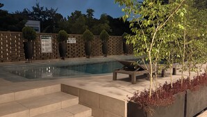 A swimming pool with steps leading down to it, surrounded by a brick wall and potted plants. - BridgeView Cantonments (Accra)