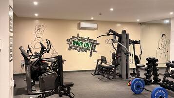 Un gimnasio con máquinas de cardio, equipo de levantamiento de pesas y decoración mural motivacional.