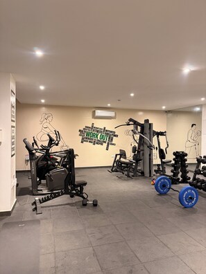 A gym with cardio machines, weightlifting equipment, and motivational wall art. - BridgeView Cantonments (Accra)